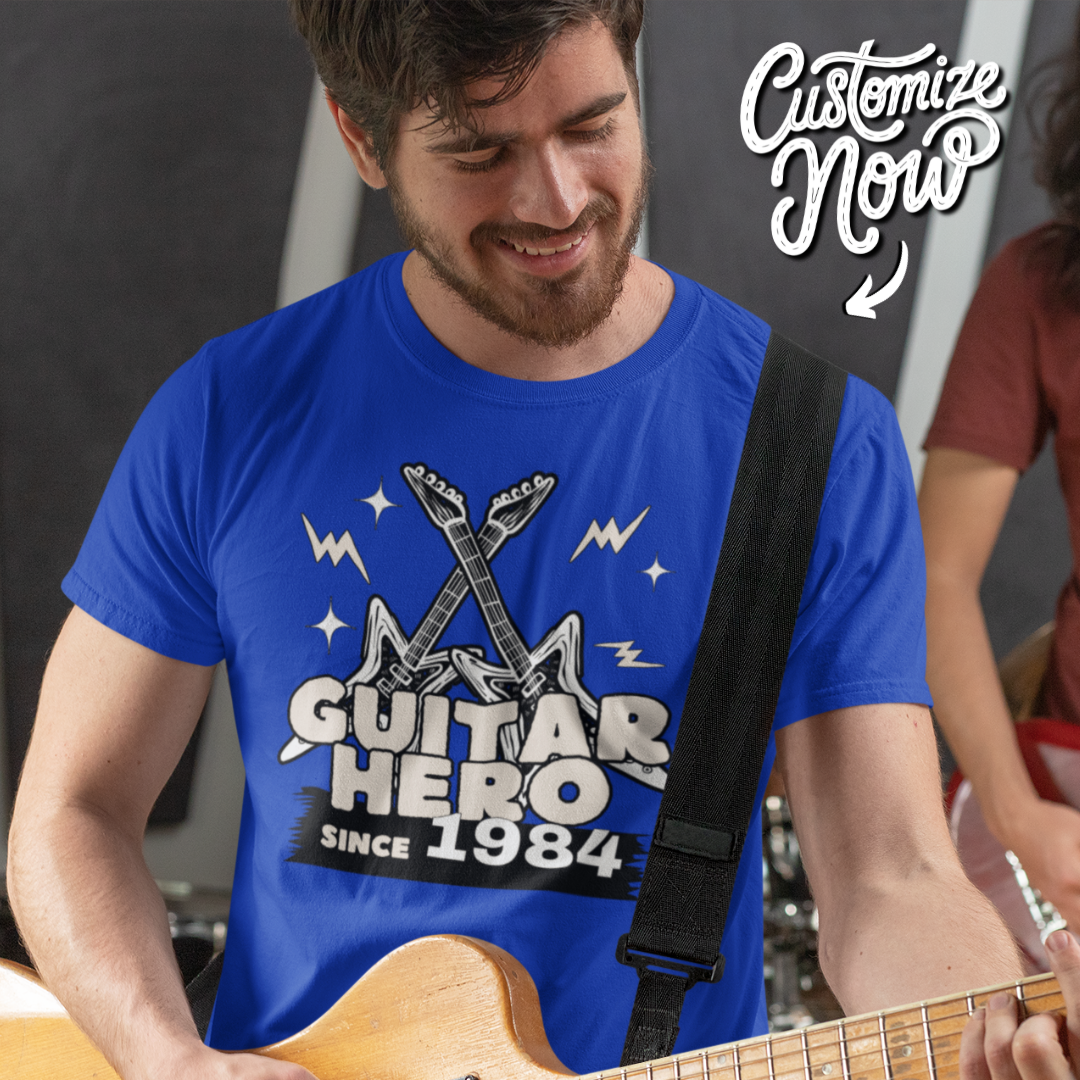 Man playing guitar wearing a blue customisable 'Guitar Hero Since...' t-shirt with a strap over his shoulder.
