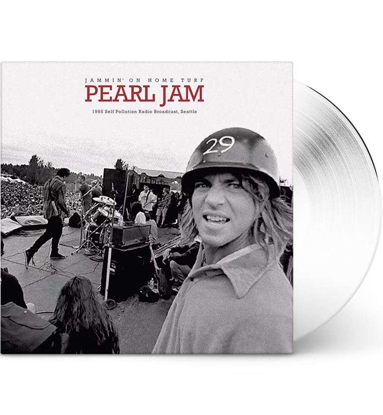 Vinyl record front cover for 'Pearl Jam Jammin’ On Home Turf.' The cover features a black-and-white photo of the band performing live on stage with a large crowd in the background. Eddie Vedder, wearing a helmet with the number 29, is prominently featured in the foreground. The title 'Pearl Jam' is displayed in red letters at the top, with 'Jammin’ On Home Turf' and '1995 Self Pollution Radio Broadcast, Seattle' written below it. The vinyl itself is white, adding a unique visual element.